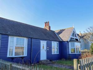 a blue house with a white door and a fence at Braeburn in Bamburgh