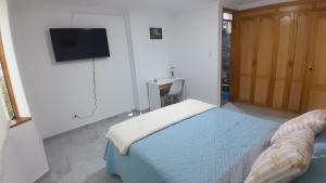 a bedroom with a bed and a flat screen tv at El Encanto in Duitama