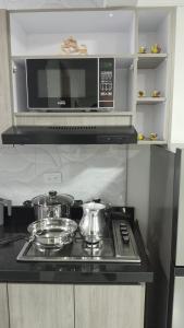 a kitchen with a microwave and two pots and pans at El Encanto in Duitama +11 photos