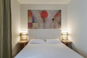 a bedroom with a white bed with a painting on the wall at Albergo Morgana in Mendrisio