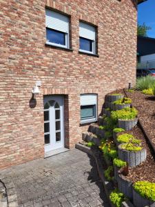 a brick building with a white door and some plants at Ferienwohnung Pommerbachquelle in Kaisersesch +11 photos