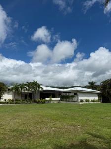 a white building with a green field in front of it at Guayacan Real Deluxe in Nicoya