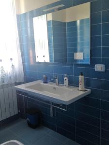 a blue tiled bathroom with a sink and a mirror at B&B La Torre in Rosello