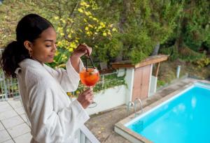 a woman holding a drink next to a pool at Albergo Morgana in Mendrisio