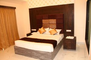 a bedroom with a large bed with a wooden headboard at sas square hotels in Tiruchirappalli