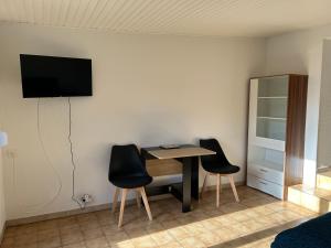 a room with a table and two chairs and a tv on the wall at Studio Le Vale - Centre Ville de Givet in Givet