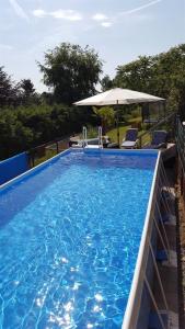 a large blue swimming pool with an umbrella and chairs at Ferienwohnung Ferien im Dorf in Bleckhausen
