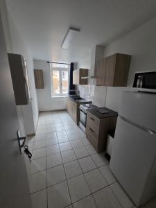 a kitchen with a refrigerator and a tile floor at Appartement Le Gwen - Centre Ville de Givet in Givet