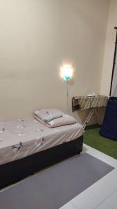 a bed in a room with a light on the wall at MQ Homestay in Temerloh