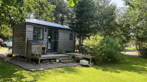 a small cabin with a porch in a yard at The Aultnamain Shepherds Hut in Wester Fearn