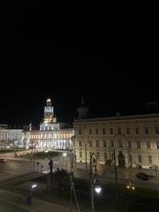 a large building with a clock tower at night at Blue Velvet Central Suite in Arad