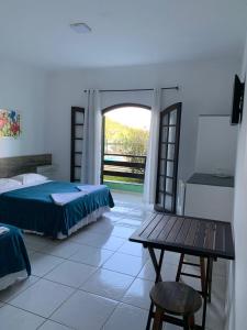 a bedroom with a bed and a table and a window at Marencanto Pousada in Ubatuba +101 photos