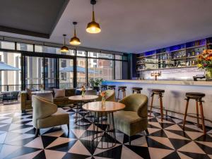 a restaurant with tables and chairs and a bar at Pullman Cape Town City Centre in Cape Town