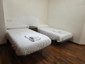 two twin beds in a small room with wood floors at Smart English Rooms in O Mesón Do Vento  +3 photos