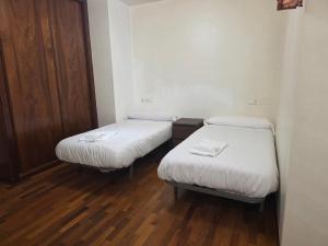 two beds in a small room with wooden floors at Smart English Rooms in O Mesón Do Vento 