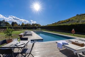 a pool with chairs and a wooden deck with a table at Borgo Malvasia- La Cascina in Sasso Marconi