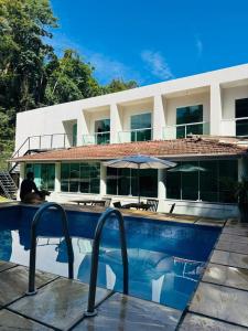 a man sitting by a swimming pool in front of a building at M&M Pousada in Petrópolis