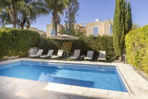 a swimming pool with chairs and an umbrella at Villa Irina Polis in Polis Chrysochous