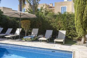 a group of chairs and an umbrella next to a pool at Villa Irina Polis in Polis Chrysochous