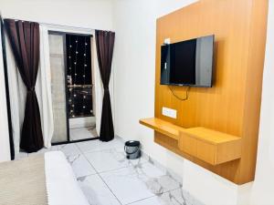 a bedroom with a tv on a wall with a window at Hotel Venus Stays Near Prestige College Bhopal in Bhopal