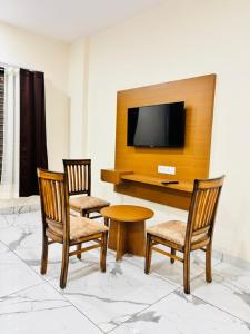 two chairs and a table with a tv on a wall at Hotel Venus Stays Near Prestige College Bhopal in Bhopal +20 photos