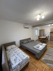 a bedroom with two beds and a dining room with a table at Apartman Spaja in Trebinje