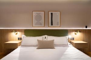 a bedroom with a large white bed with two lights at Hotel Core Suites Estadio Akron in Zapopan