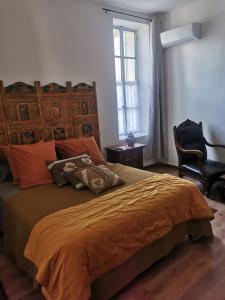 a bedroom with a bed with an orange blanket and a chair at Côté fontaine in Orange