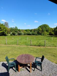 a wooden table and two chairs sitting next to a field at La roulotte de Rochavelle in Chiché