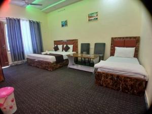a hotel room with two beds and a table at Raj Hotel and Restaurant in Bhadarwāh