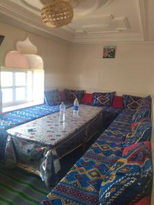 a room with a couch and a table with water bottles on it at Maison Ighrem in Idoukaln