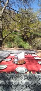 a table with plates of food on a red table cloth at Maison Ighrem in Idoukaln