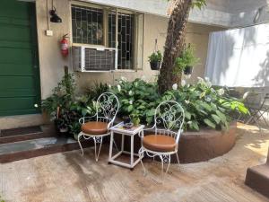 two chairs and a table in front of a house at Cosy studio at Delphi bungalow in Mumbai
