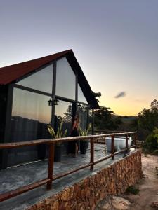 a woman sitting on the deck of a glass house at Cabana Pegasus in Ibicoara