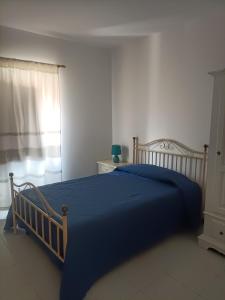 a bedroom with a blue bed and a window at La casa di Nonna Carta in Fordongianus