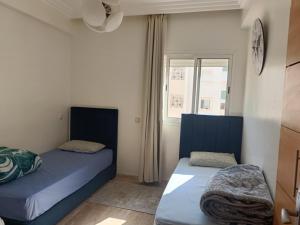 two beds in a room with a window at Cosy appart 3p in Rabat