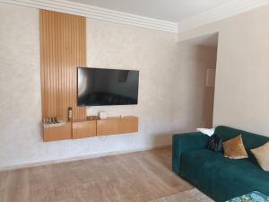 a living room with a green couch and a flat screen tv at Cosy appart 3p in Rabat