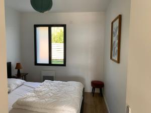 a white bedroom with a bed and a window at Le Moutchic in Lacanau
