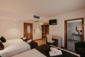 a hotel room with two beds and a desk at La Trobada Hotel Sport in Ripoll