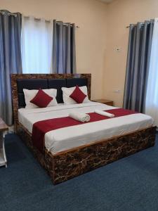 a bedroom with a large bed with red pillows at Raj Hotel and Restaurant in Bhadarwāh +8 photos