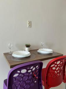 a table with two chairs and two plates and glasses at Boulevard Plaza Flat Mirante Apto 201 in Campina Grande