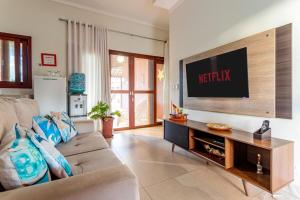 a living room with a couch and a flat screen tv at Refúgio Gostoso in São Miguel do Gostoso