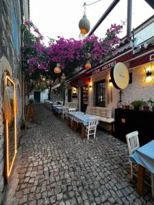 a restaurant with tables and purple flowers on a street at Alaçatı Disa in Alaçatı