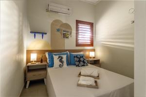 a bedroom with a large white bed with blue pillows at Refúgio Gostoso in São Miguel do Gostoso