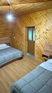 a room with two beds in a wooden cabin at Bujtina Vellezerit Grrela in Theth