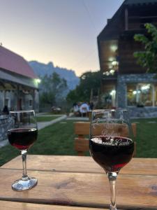 two glasses of wine sitting on a wooden table at Bujtina Vellezerit Grrela in Theth