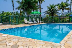 a swimming pool with chairs and an umbrella at Marencanto Pousada in Ubatuba
