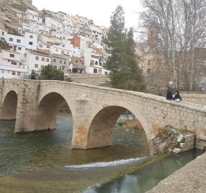 two people sitting on a bridge over a river at Casa Dulcinea in Alborea