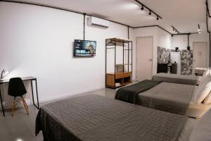 a room with two beds and a tv on the wall at VILLA BILAC - Large Studios close to Vila Germânica in Blumenau