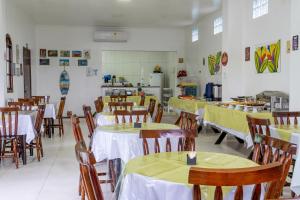 a dining room with tables and chairs with yellow table cloth at Marencanto Pousada in Ubatuba